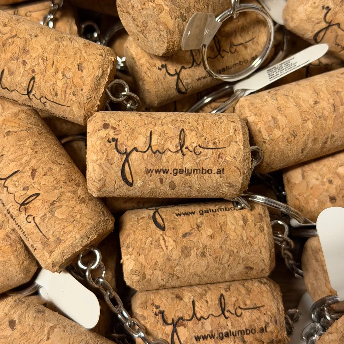 Ein Stapel Schlüsselanhänger "Weinkorken" mit Gravur mit "galumbo" und einer Website in schwarzer Schrift.