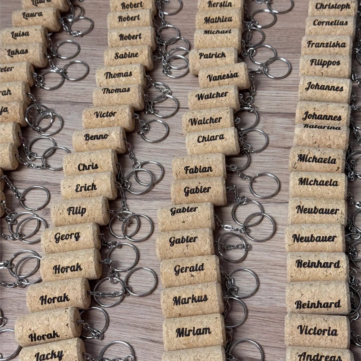 Schlüsselanhänger "Weinkorken" mit individueller Gravur - personalisierte Namens-Anhänger auf Holzfläche präsentiert.